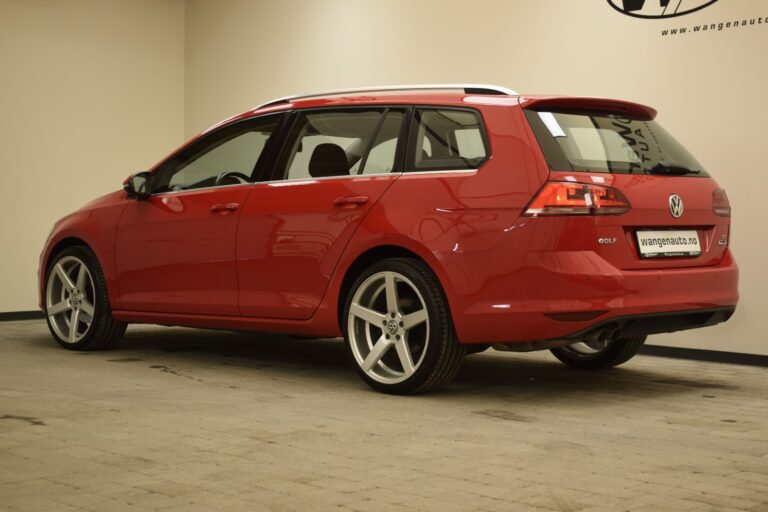 A red Volkswagen Golf station wagon is parked in an indoor space with a beige wall background.