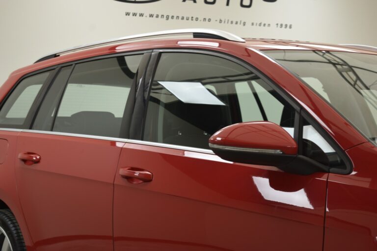 A red SUV is shown from the side, highlighting the driver's side door, windows, and side mirror in a showroom with a sign in the background.