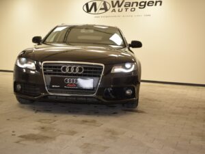 A black Audi sedan is parked indoors on a tiled floor with the logo and name "Wangen Auto" displayed on the wall behind it.