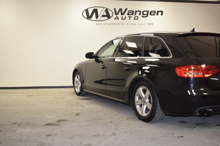 A black station wagon is parked indoors on a grey, tiled floor in front of a white wall with the text "Wangen Auto" and a website URL in black letters. .