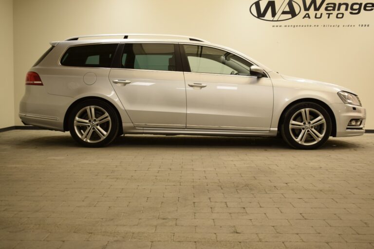 A silver station wagon is parked indoors on a tiled floor. The vehicle is viewed from the side. The logo and text for Wange Auto are visible on the wall in the background.