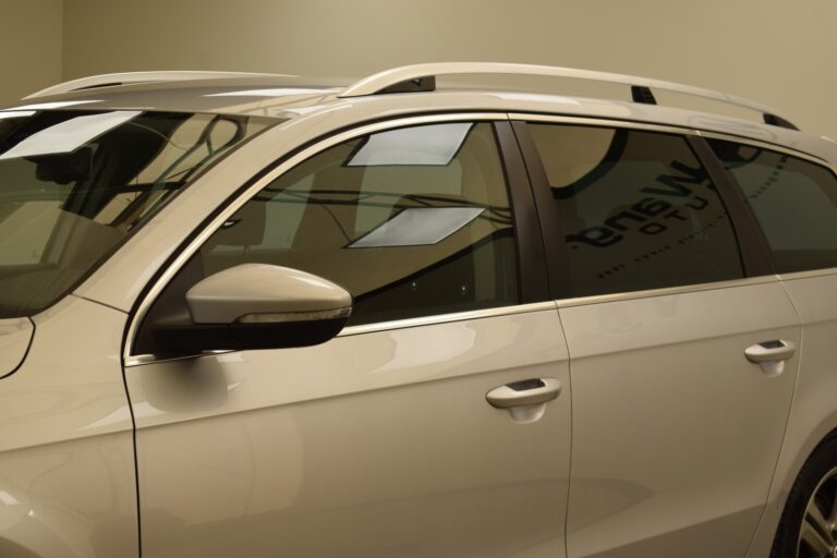 Close-up view of the side and part of the roof of a white SUV with tinted windows and a roof rack in an indoor environment.