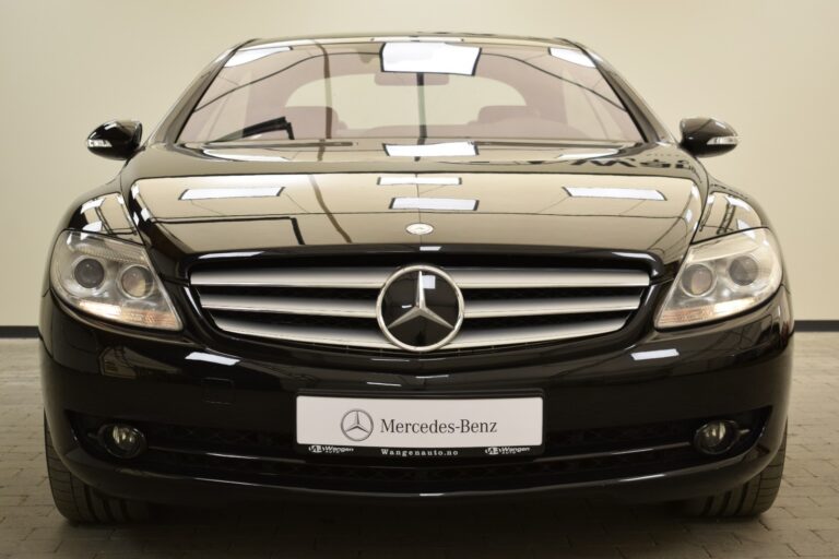 A black Mercedes-Benz car is parked in an indoor space, showing its front view. The logo and grille are prominently displayed.