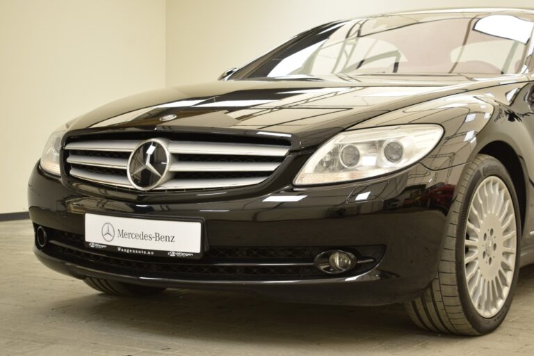 Front view of a black Mercedes-Benz car displaying its grille, headlights, and part of its hood and wheel.