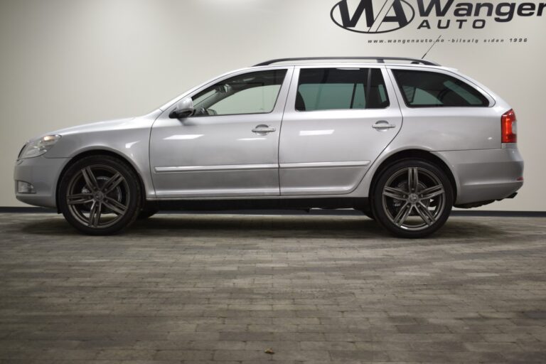 A silver station wagon parked indoors on a brick floor, viewed from the side. A logo and text for "Wanger Auto" are visible on the wall in the background.