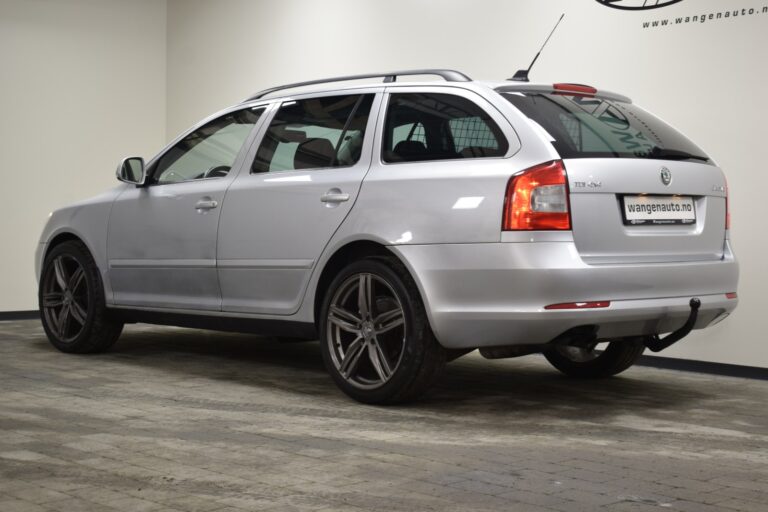 A silver station wagon is parked indoors, angled to show the rear and driver's side. The vehicle has dark alloy wheels and a rooftop antenna.