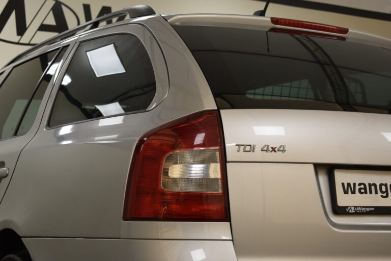 A rear view of a silver wagon vehicle with "TDI 4x4" badge on the back, showing a taillight and a branded license plate.