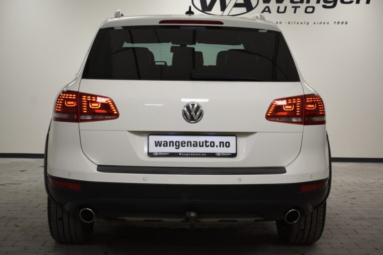 Rear view of a white Volkswagen SUV with a visible "wangenauto.no" dealership plate, brake lights illuminated, displayed indoors on a tiled floor background.