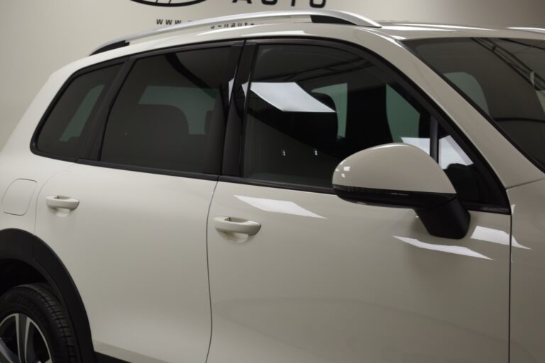 Close-up side view of a white SUV with tinted windows, showcasing the rear door and part of the front door. The vehicle is under indoor lighting.