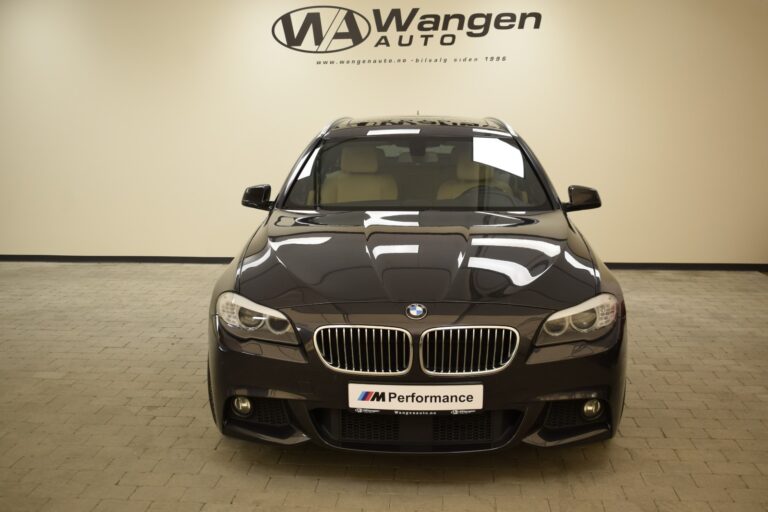 Front view of a black BMW car with an "M Performance" license plate situated in a showroom with Wangen Auto branding on the wall behind it.