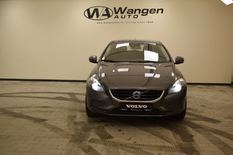 Front view of a gray Volvo car in a showroom with "Wangen Auto" signage on the wall behind it.