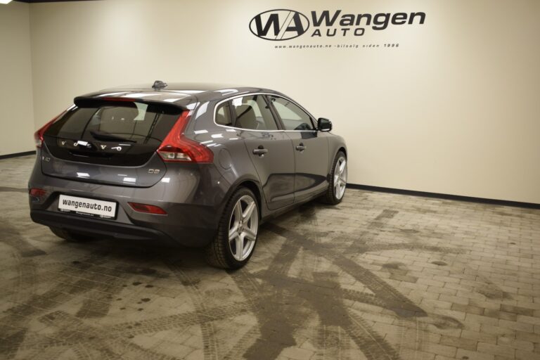 A gray Volvo V40 D2 parked in an indoor showroom of Wangen Auto. The car is shown from the rear three-quarters view.