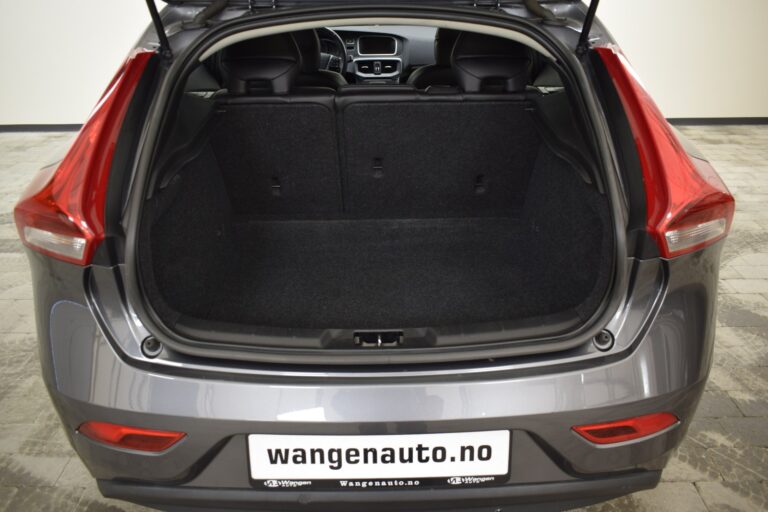 A grey car's rear view with its trunk open, revealing a spacious, empty cargo area. A website URL "wangenauto.no" is visible on the license plate.