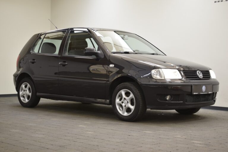 A stationary black Volkswagen Polo hatchback is parked indoors on a tiled floor, facing slightly to the right.