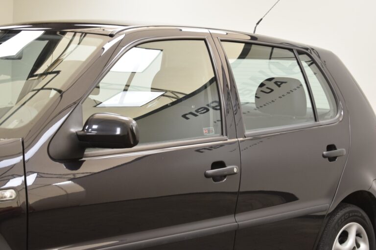 Side view of a black, four-door car in a well-lit indoor space, showcasing the doors, windows, and side mirror.