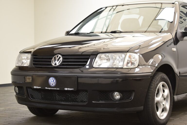 Close-up view of a black Volkswagen car parked indoors, showing the front grille and headlights.