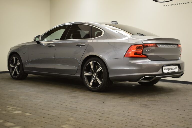 A gray sedan parked indoors on a textured floor, viewed from the rear and left side. The car features sleek lines and modern taillights.