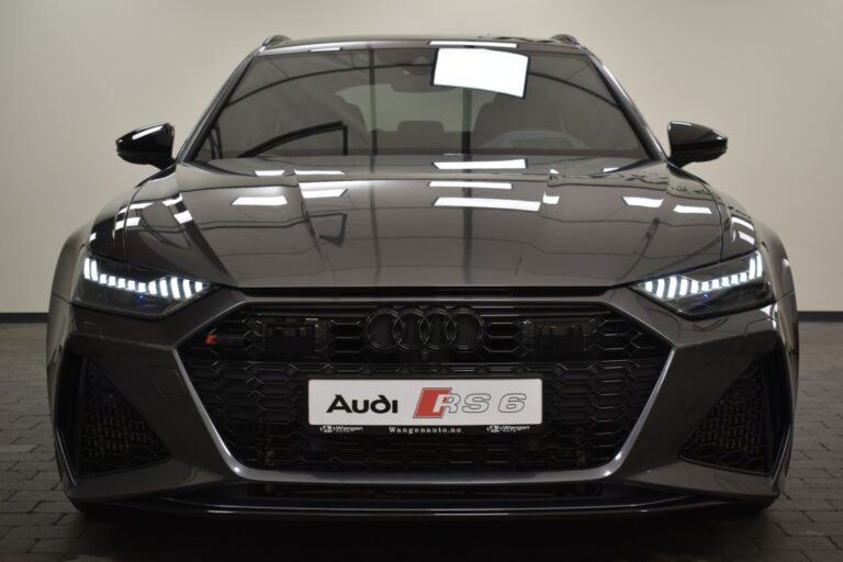 Front view of a gray Audi RS6, displaying its grille, headlights, and logo. The vehicle is parked indoors on a tiled floor.