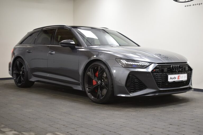 A sleek, metallic gray Audi RS6 Avant is parked inside showcasing its sporty design, black rims, and red brake calipers.