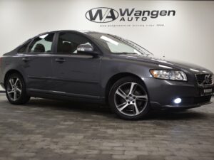 A gray Volvo sedan parked indoors on a tiled floor with the brand "Wangen Auto" displayed on the wall in the background.