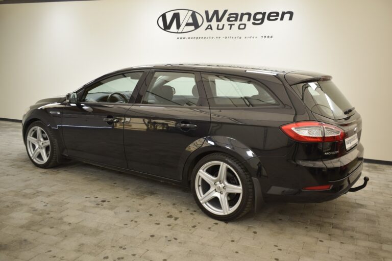 A black station wagon is displayed in a showroom with a "Wangen Auto" logo on the wall in the background.