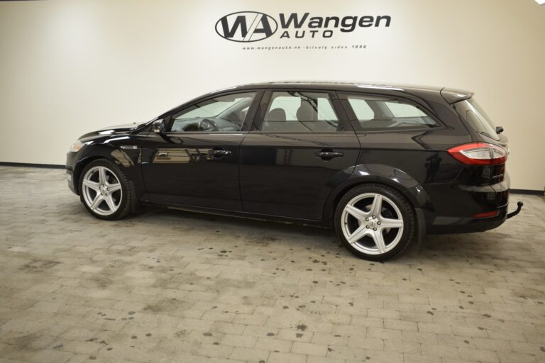 Side view of a black station wagon car parked indoors at a dealership, with a "Wangen Auto" sign on the wall in the background.