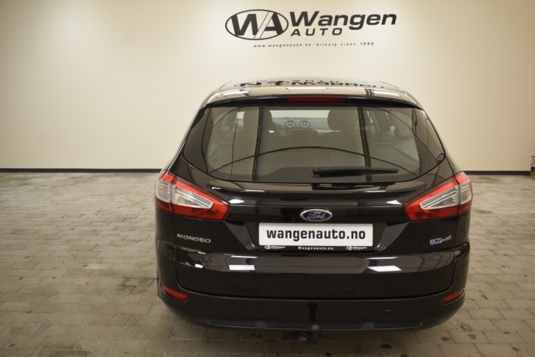 Black Ford Mondeo parked inside a showroom with a "Wangen Auto" sign on the wall and a "wangenauto.no" license plate.